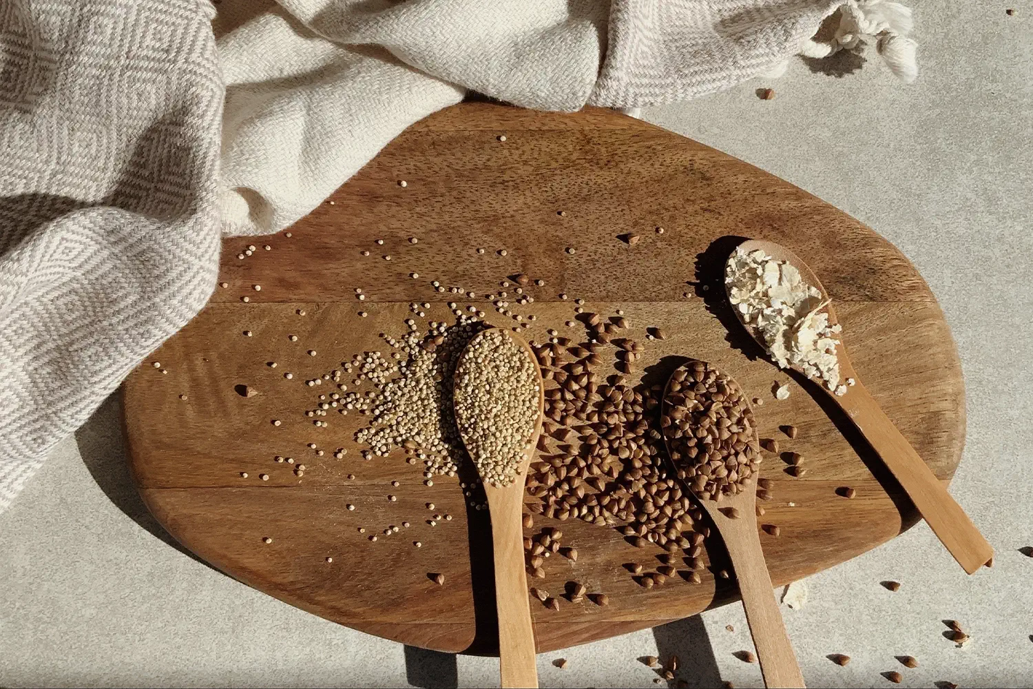 three spoonfuls of different gains on a wooden surface surrounded by a beige cloth